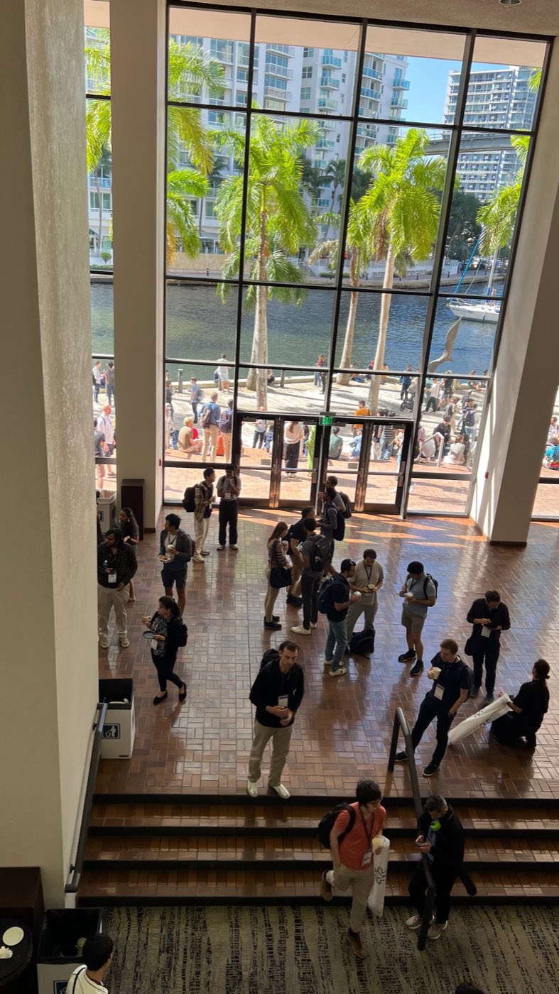 Attendees in the waterfront atrium of the EMNLP 2024 venue in Miami
