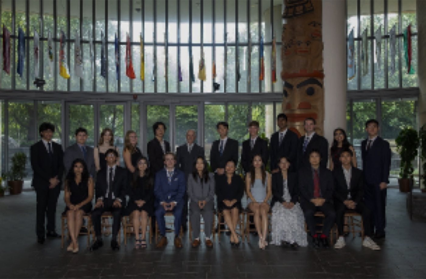 Formal Algoverse program group photo in a flag-lined atrium