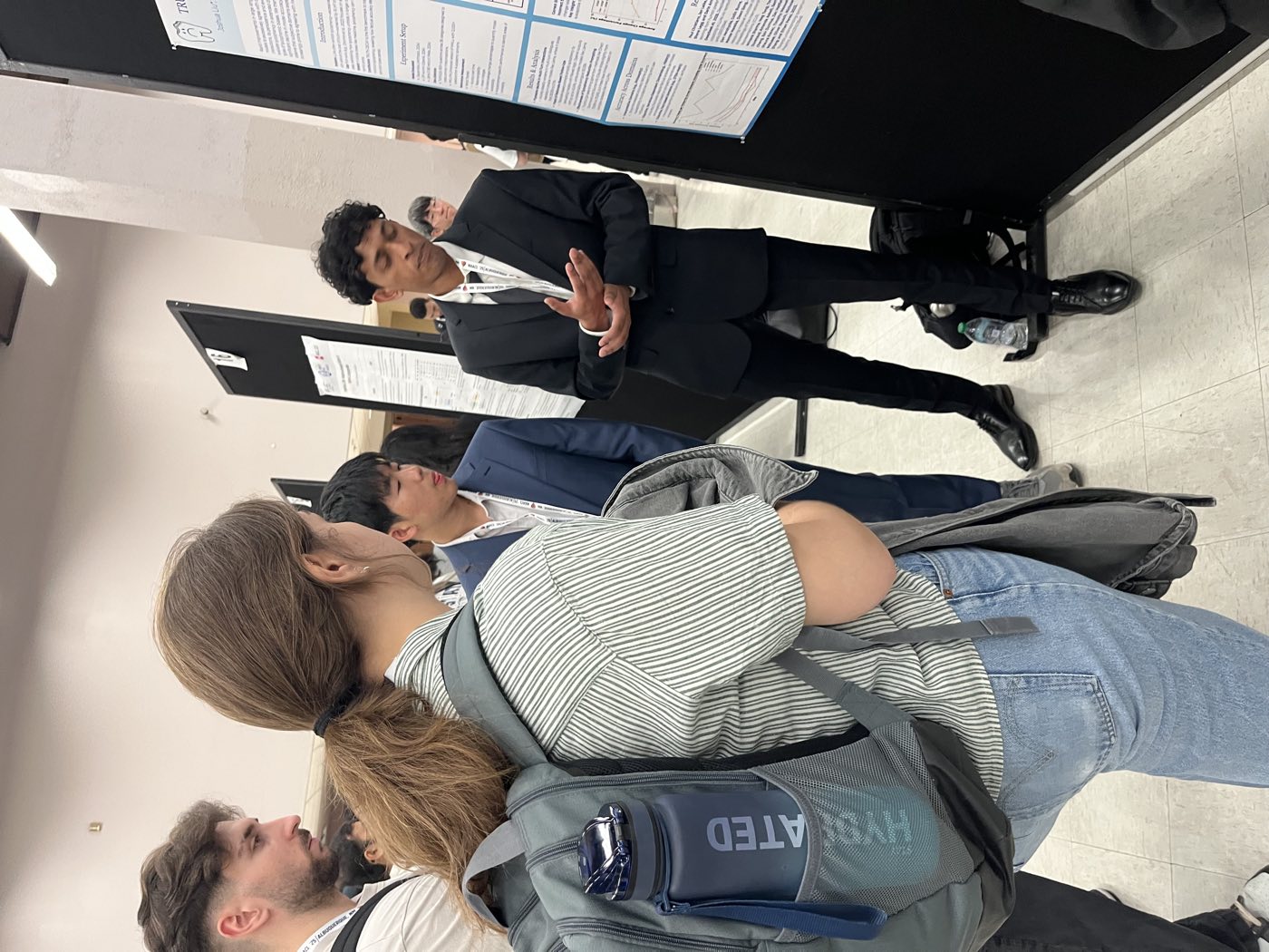 Algoverse student in suit presenting research poster to attendees at NAACL 2025